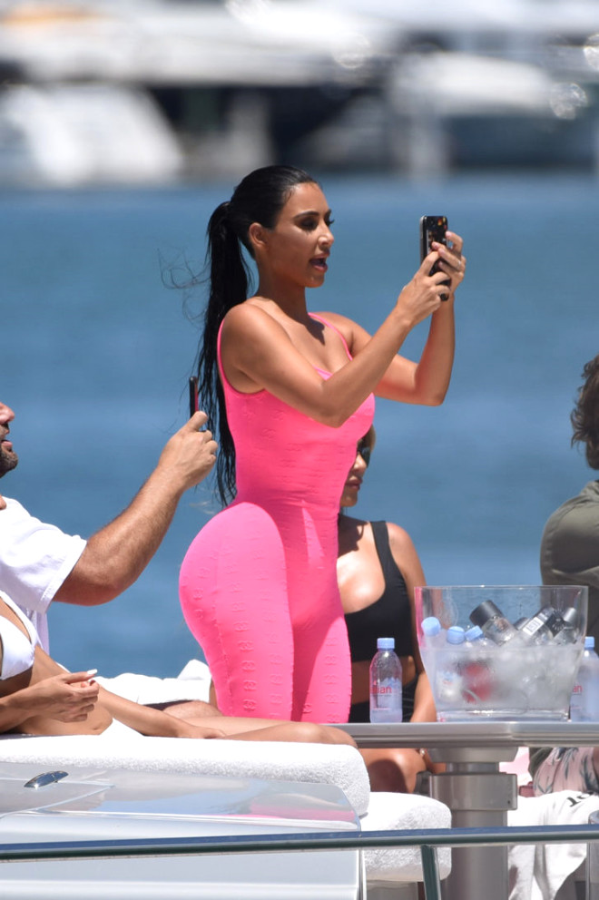 37 yandaki Kim Kardashian, ocuklaryla birlikte kt tekne turunda fosforlu pembe bir tayt tulum giydi.