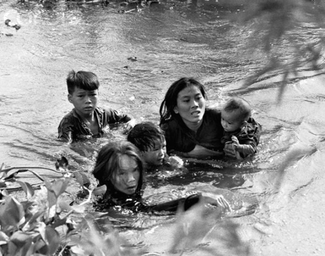 Bir anne ve ocuklar, Amerikan bombalarndan kamak iin Gney Vietnamdaki nehri gemeye alyorlar. Fotoraf: Kyoichi Sawada, Japonya / 1965